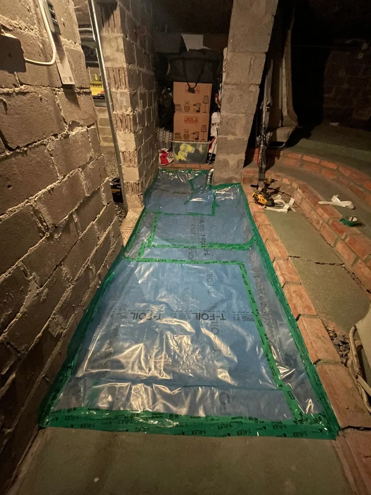 Plastduk tejpad mot väggarna på källargolvet, tätning som hindrar radon från att komma upp genom grunden