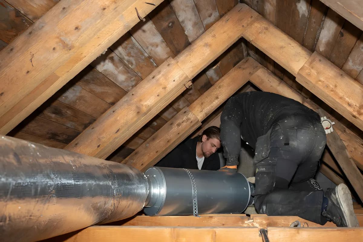 Två ventilationstekniker som monterar spirorör på en vind vid FTX-installation i Stockholm