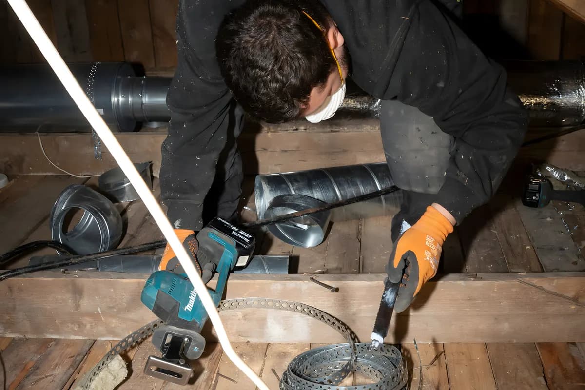 Ventilationstekniker med verktyg vid kanaler på en vind inför ventilationsrengöring i Stockholm